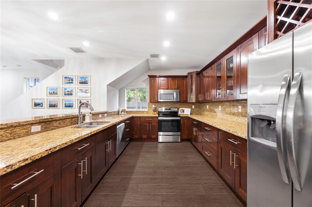 834 Southwest 16th Street Fort Lauderdale, FL 33315 - Photo 11 of 26 a large kitchen with stainless steel appliances kitchen island granite countertop a large counter top a sink and a refrigerator