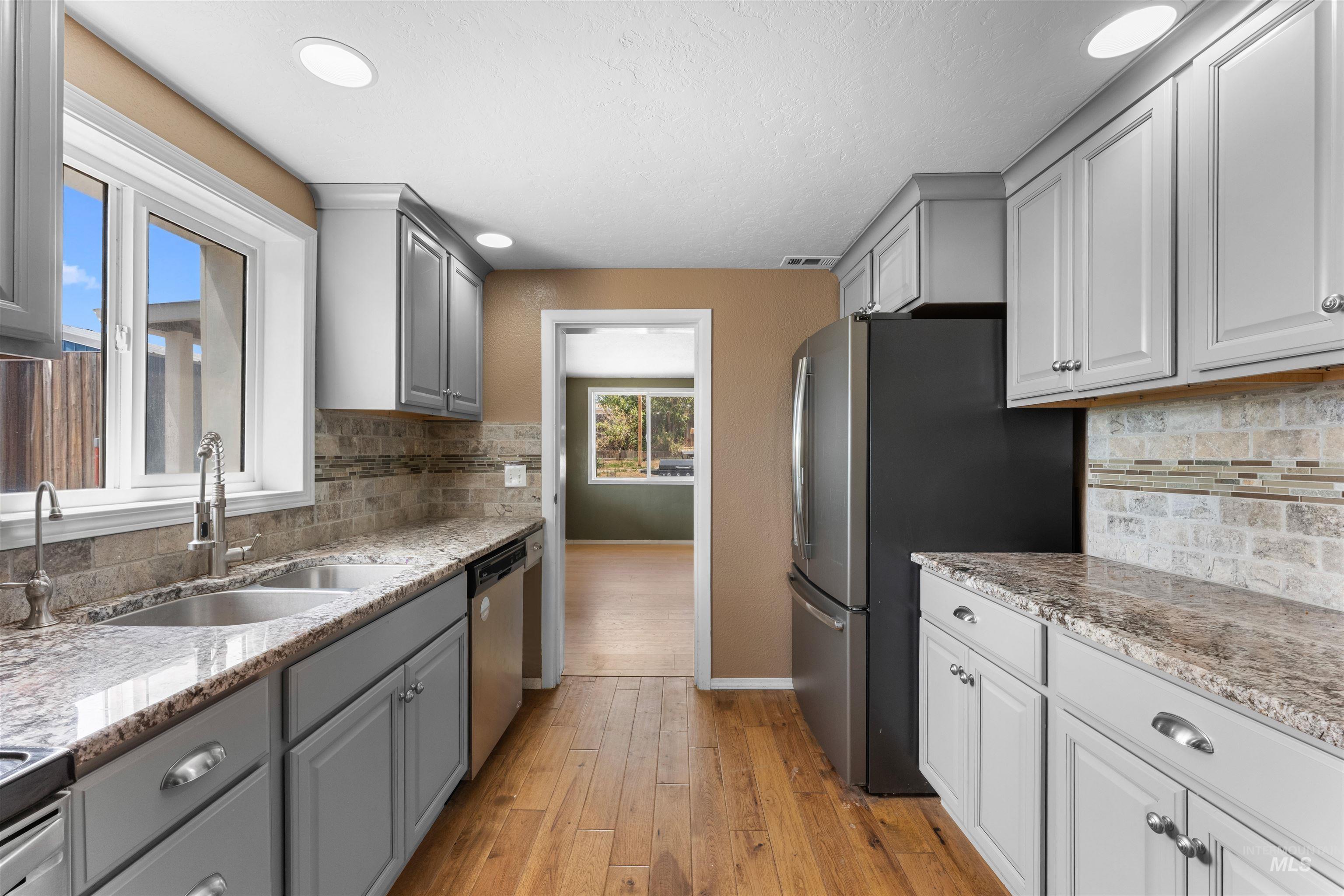 17441 Upper Pleasant Ridge Road Caldwell, ID 83607 - Photo 12 of 40 Galley kitchen featuring light gray cabinetry, wood-finish flooring, recessed lighting, and stone countertops