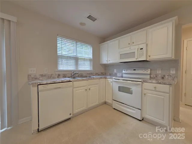 a kitchen with granite countertop white cabinets white stainless steel appliances with a sink and dishwasher