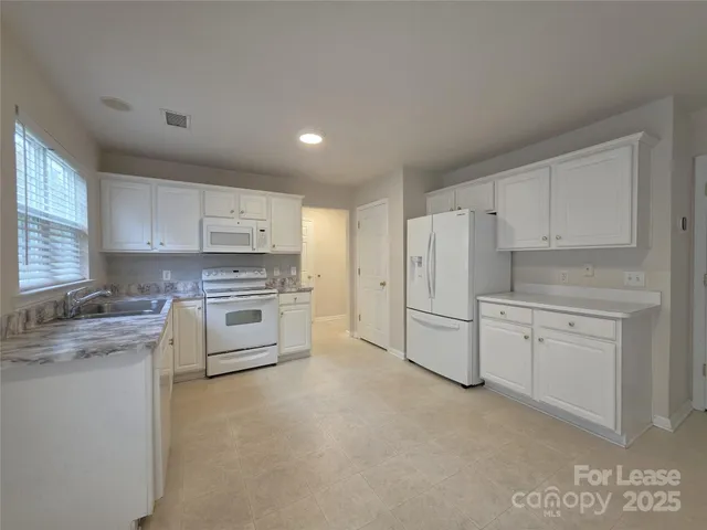 a kitchen with white cabinets and white appliances