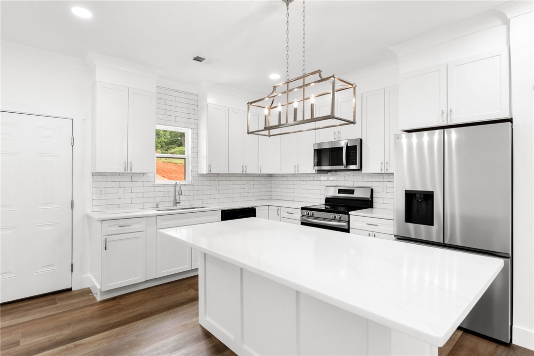 914 Smith Grove Road Easley, SC 29640 - Photo 9 of 37 A spacious kitchen features bright white cabinetry, a large central island, and modern stainless steel appliances.