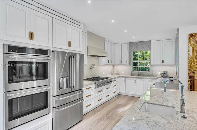a kitchen with granite countertop white cabinets and stainless steel appliances