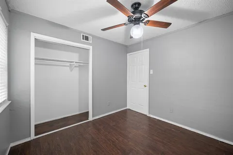 an empty room with wooden floor fan and windows