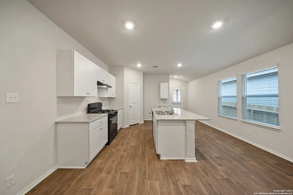 a large kitchen with stainless steel appliances a large counter top a sink a stove and a refrigerator