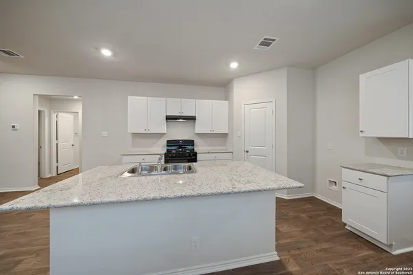 a kitchen with kitchen island granite countertop a sink a counter top space and cabinets