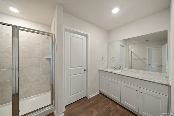 a bathroom with a granite countertop sink a mirror and a shower
