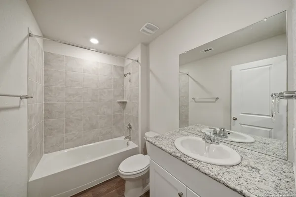 a bathroom with a granite countertop sink toilet mirror and bathtub