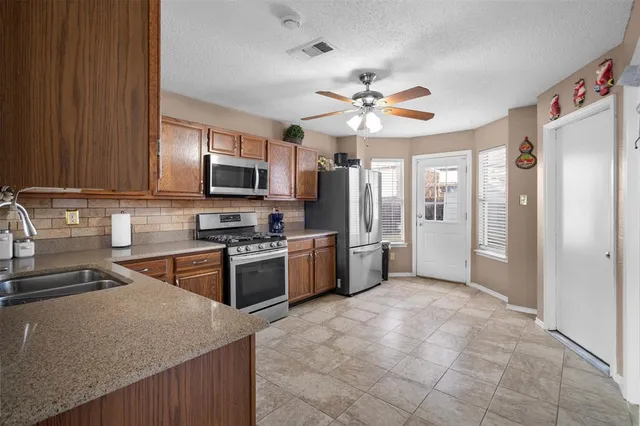 a kitchen with stainless steel appliances granite countertop a refrigerator a stove top oven a sink and dishwasher