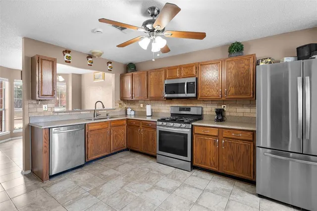 a kitchen with stainless steel appliances granite countertop a refrigerator a stove a sink a washer dryer and a refrigerator