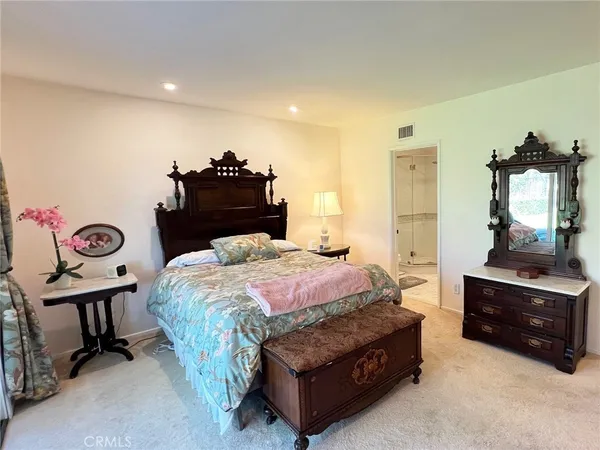 a spacious bedroom with a bed and a dresser in it