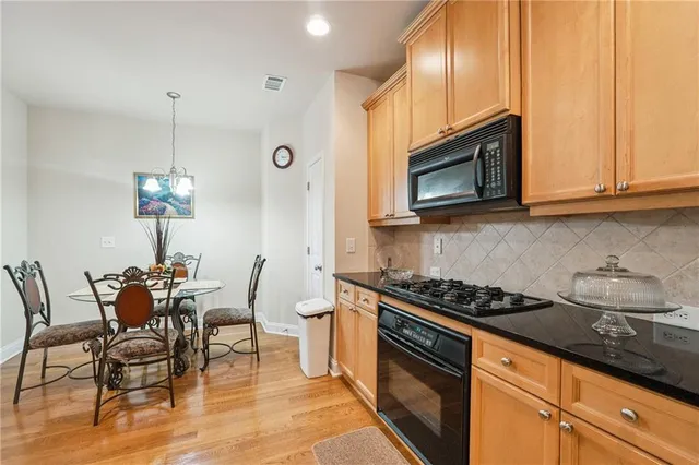 a kitchen with granite countertop a stove chairs and microwave