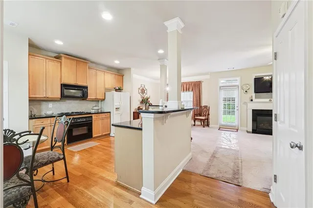 a kitchen with stainless steel appliances kitchen island granite countertop a stove top oven a sink a dining table and chairs