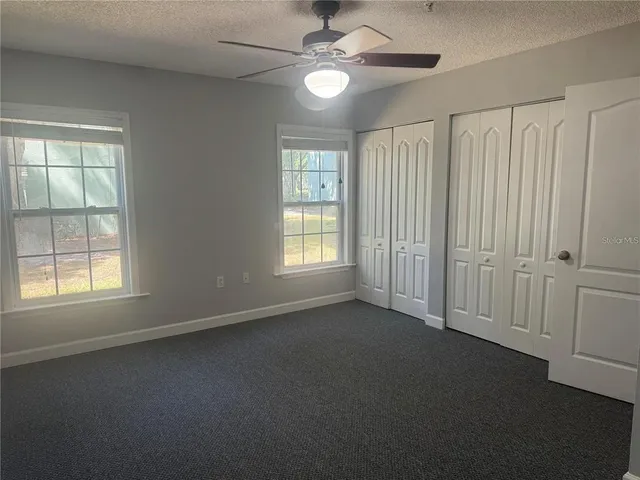an empty room with windows and fan