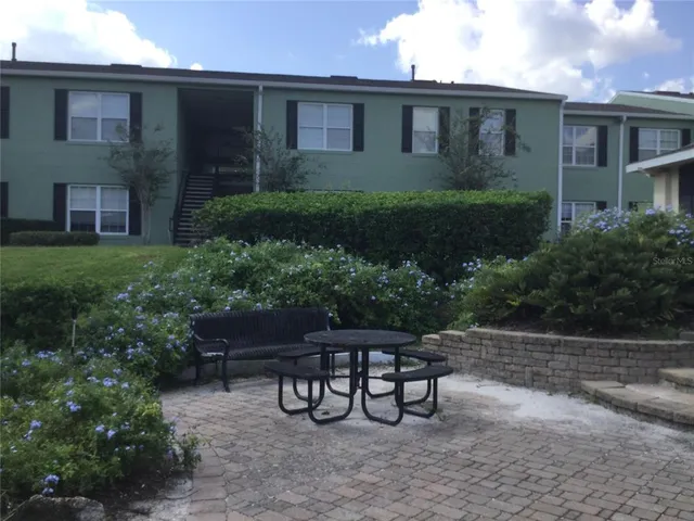 a backyard of a house with table and chairs plants
