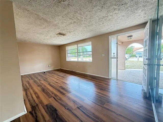 a view of a hallway with wooden floor and a bathroom