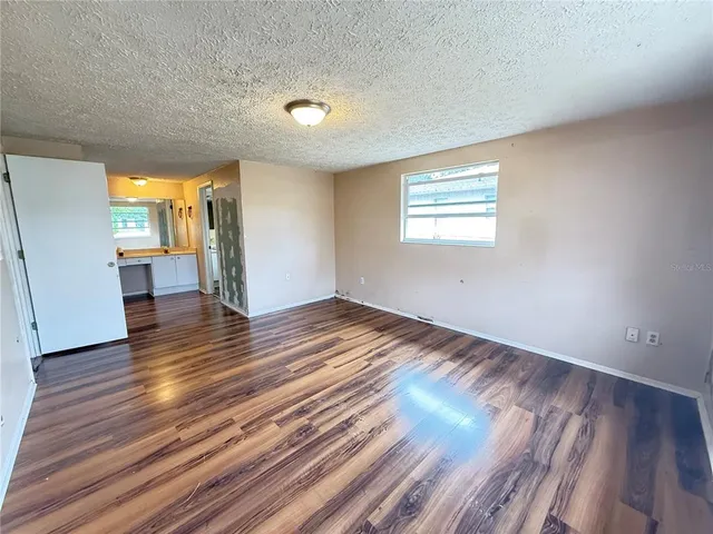 a view of an empty room with window and wooden floor