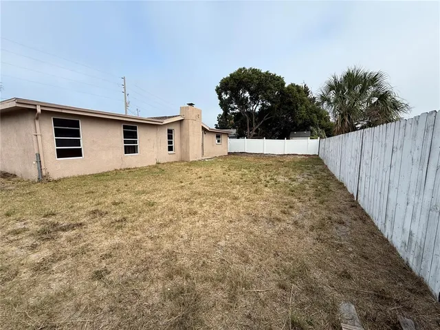 an empty room with wooden floor fireplace and windows