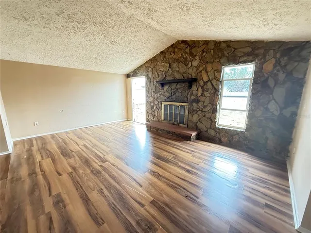 a view of empty room with wooden floor and fireplace