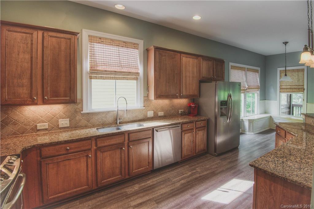 122 Mills Lane Fort Mill, SC 29708 - Photo 8 of 36 a kitchen with stainless steel appliances granite countertop a refrigerator a sink dishwasher and wooden cabinets with wooden floor