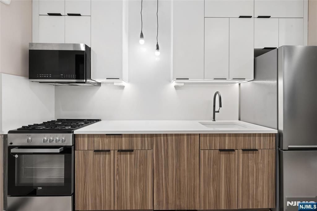 208 15th Street Jersey City, NJ 07310 - Photo 27 of 46 a kitchen with stainless steel appliances a microwave a sink and cabinets