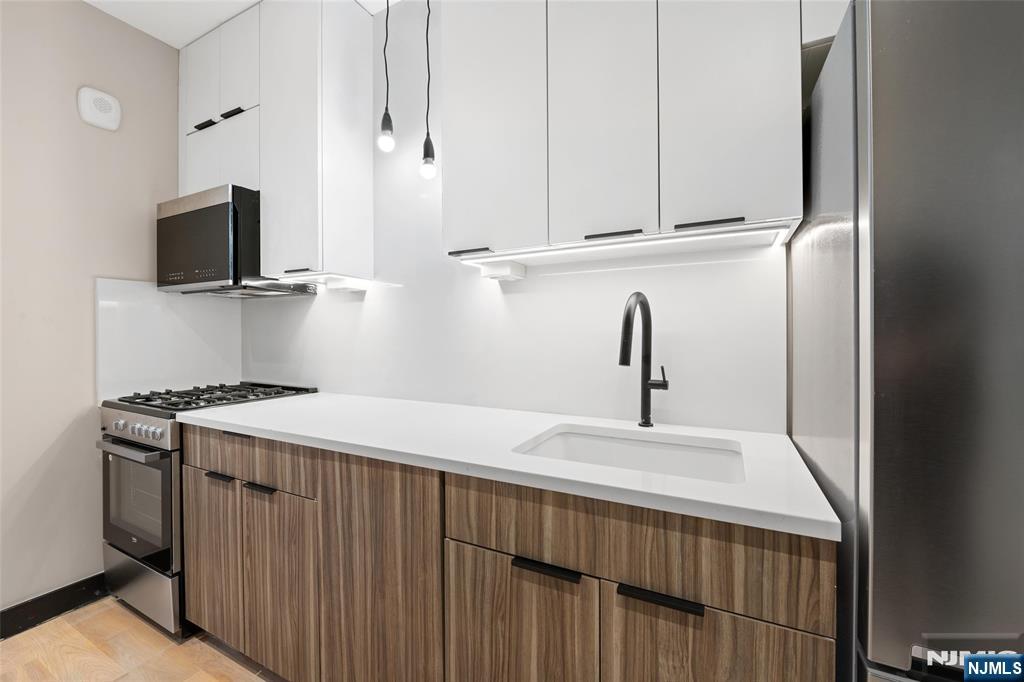 208 15th Street Jersey City, NJ 07310 - Photo 29 of 46 a kitchen with a sink and a stove top oven with wooden floor