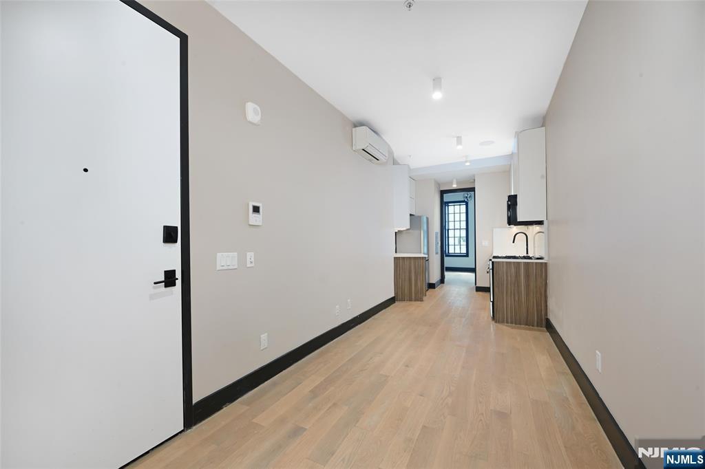 208 15th Street Jersey City, NJ 07310 - Photo 7 of 46 a view of a hallway with wooden floor and a kitchen