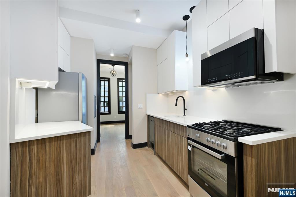 208 15th Street Jersey City, NJ 07310 - Photo 9 of 46 a kitchen with stainless steel appliances a stove microwave and sink