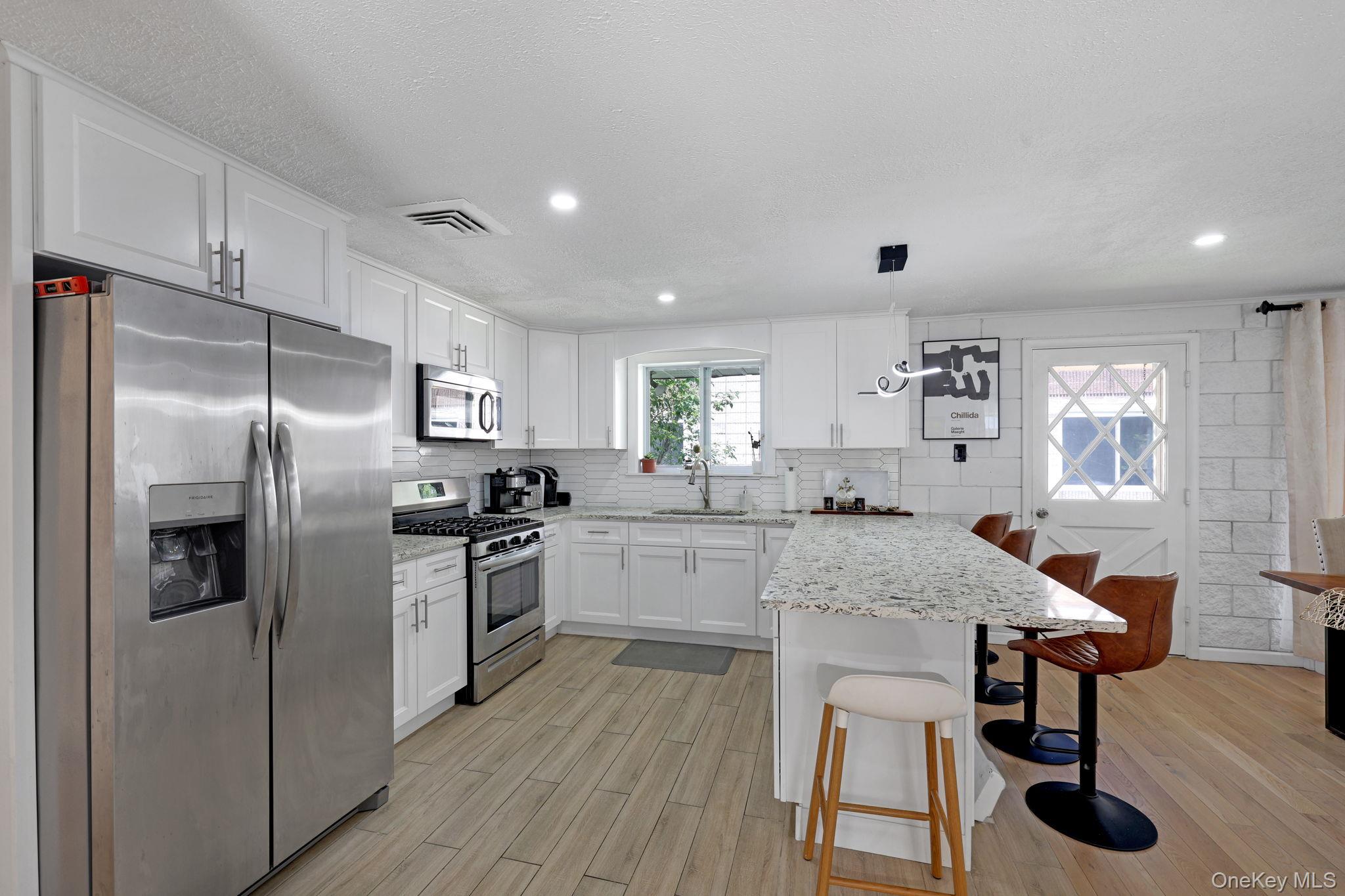 35 Kroeger Road Monticello, NY 12701 - Photo 5 of 29 a kitchen with stainless steel appliances granite countertop a refrigerator a sink dishwasher a stove and white cabinets with wooden floor