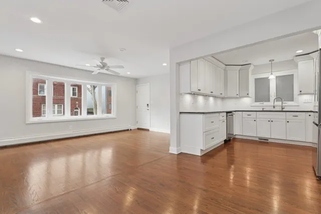 a view of an empty room with a window and wooden floor