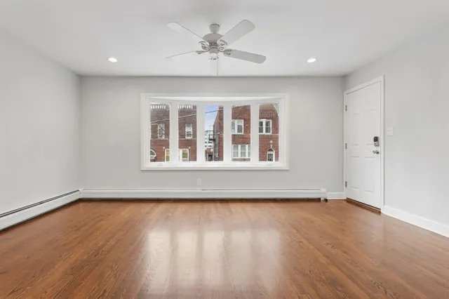 a view of an empty room with wooden floor and a window