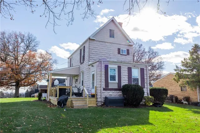 a front view of a house with garden and trees