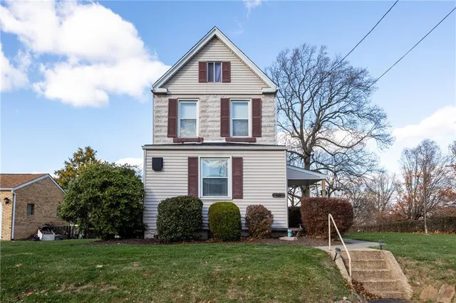 a front view of a house with a garden and trees
