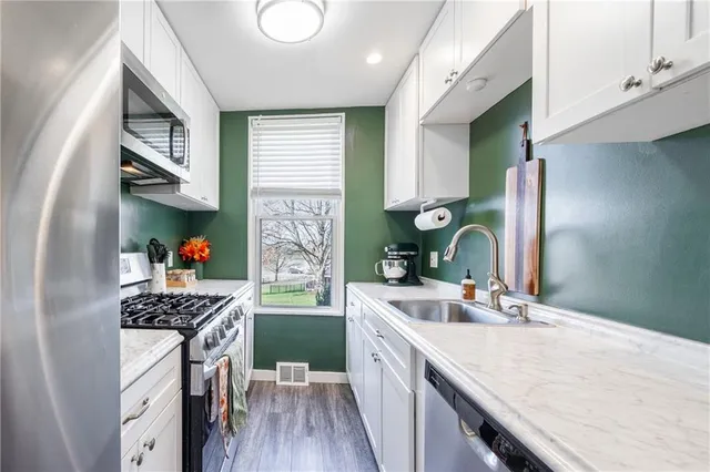 a kitchen with stainless steel appliances a sink stove and cabinets
