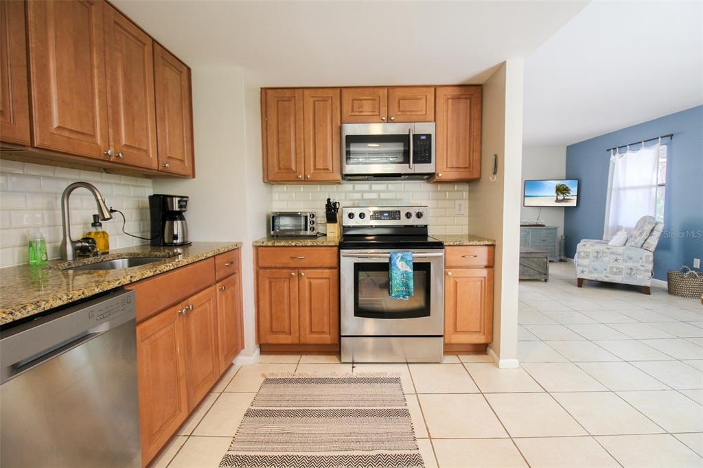 1116 Royal Road Venice, FL 34293 - Photo 15 of 26 a kitchen with stainless steel appliances granite countertop a stove top oven a sink dishwasher and a microwave oven on the blue kitchen countertops