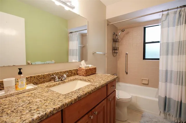 a bathroom with a granite countertop sink a toilet and shower