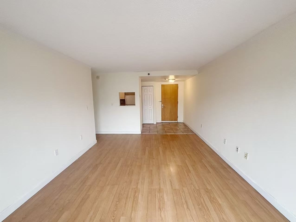 15 North Beacon Street, Unit 217 Boston, MA 02134 - Photo 2 of 21 an empty room with wooden floor and windows