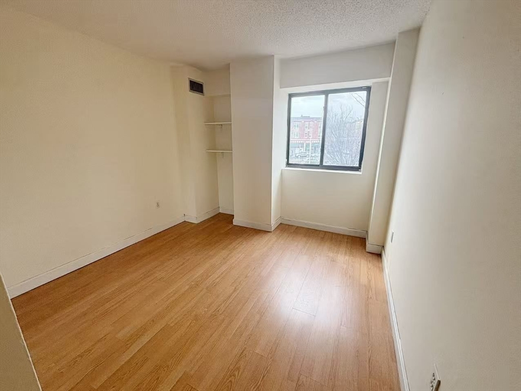 15 North Beacon Street, Unit 217 Boston, MA 02134 - Photo 5 of 21 an empty room with wooden floor and windows