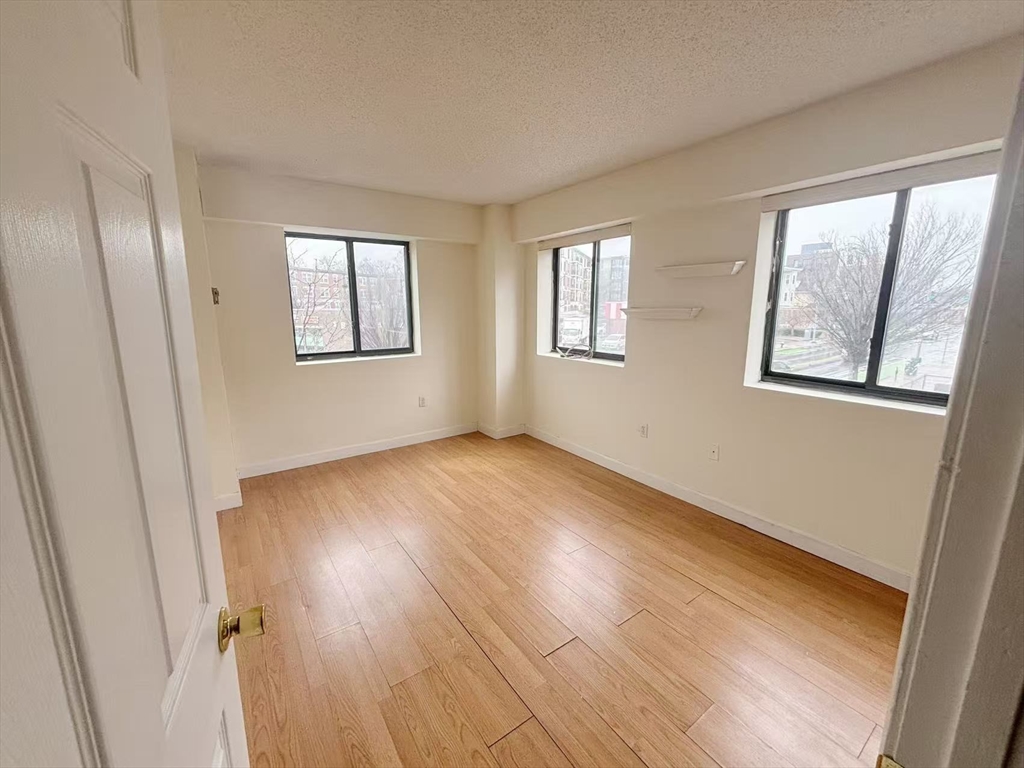 15 North Beacon Street, Unit 217 Boston, MA 02134 - Photo 8 of 21 a view of an empty room with wooden floor and a window