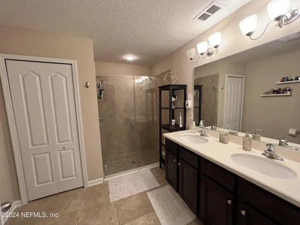 a bathroom with a double vanity sink mirror and shower