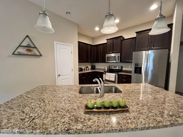 a kitchen with stainless steel appliances granite countertop a sink refrigerator and microwave