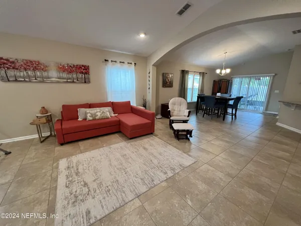 a living room with furniture and a dining table with wooden floor