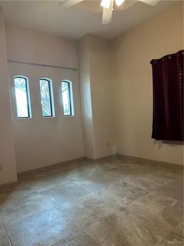 an empty room with chandelier fan and glass door