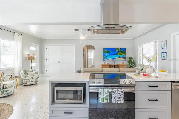 a living room with stainless steel appliances kitchen island granite countertop a stove and a sink