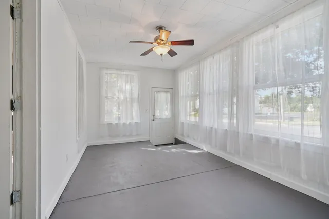 an empty room with ceiling fan and window