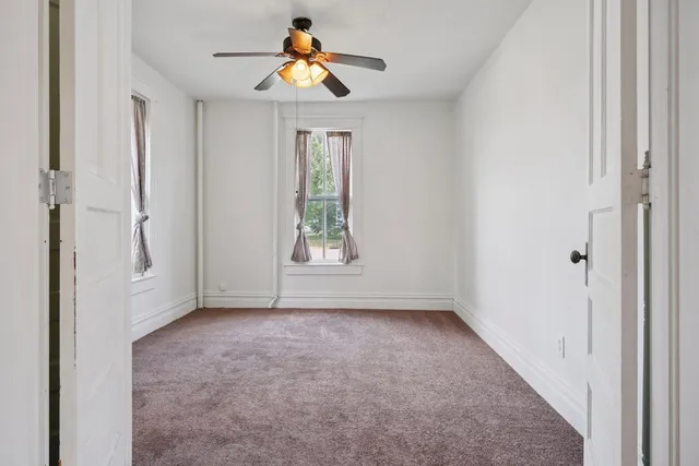 an empty room with windows and ceiling fan