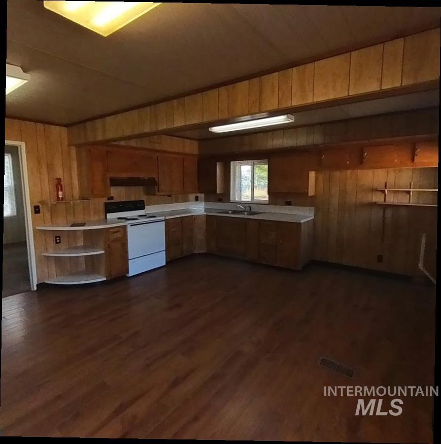 418 13th Street Clarkston, WA 99403 - Photo 15 of 26 Kitchen with wood walls, white electric range oven, light countertops, dark wood-type flooring, and open shelves