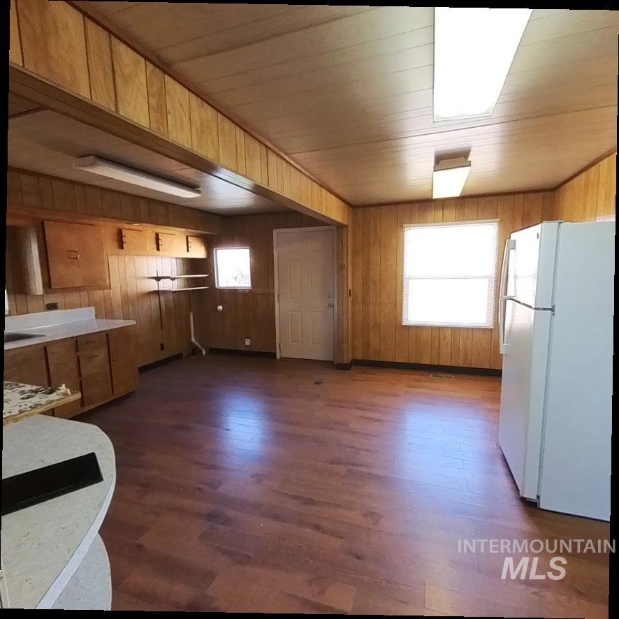 418 13th Street Clarkston, WA 99403 - Photo 16 of 26 Kitchen with freestanding refrigerator, wooden walls, dark wood-type flooring, brown cabinetry, and light countertops