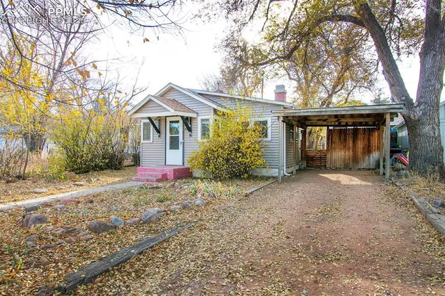 a view of a house with a yard and large tree