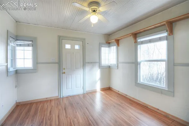 a view of an empty room with wooden floor and a window