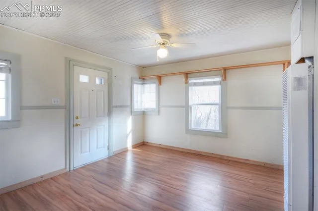 a view of an empty room with wooden floor and a window